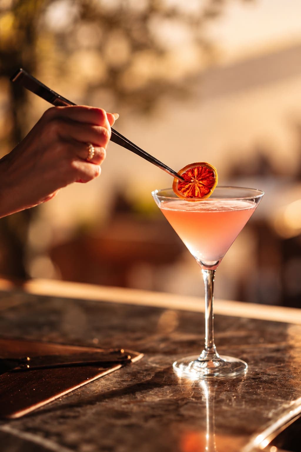 Cocktail roz cu felie de portocală, pe blatul barului